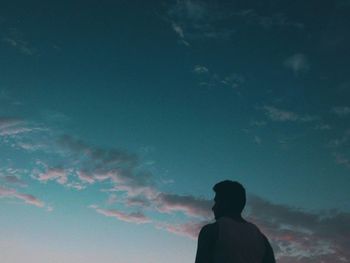 Rear view of silhouette man standing against blue sky