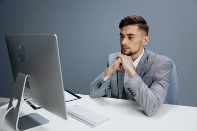 Young man using laptop at desk in office