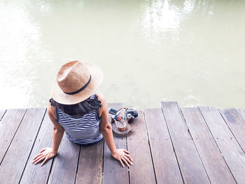 High angle view of man sitting on pier over lake