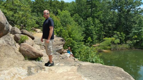 Full length of man standing on rock by lake