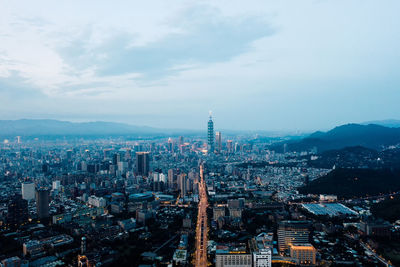 High angle view of city buildings against cloudy sky