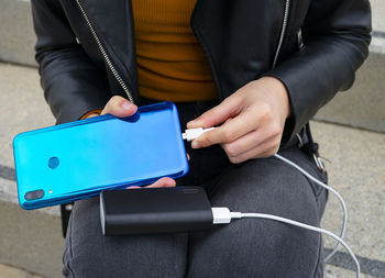 Woman connecting the mobile to a powerbank.