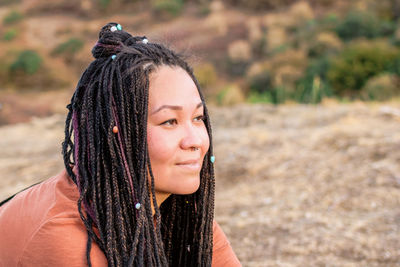 Close up portrait of beautiful european woman with long african braids on a background of nature.