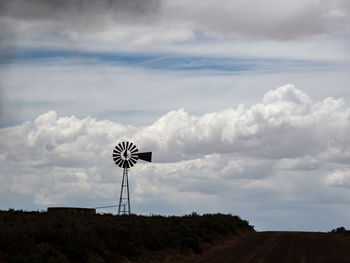 Silhouette windmill on land against sky