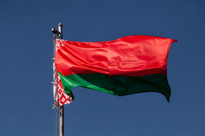 Low angle view of red flag against blue sky