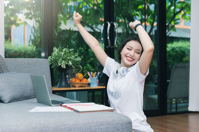 Smiling young woman using smart phone at table