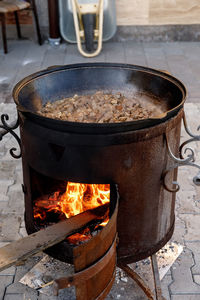 A huge amount of lamb pilaf in the process of cooking in a cauldron over an open fire