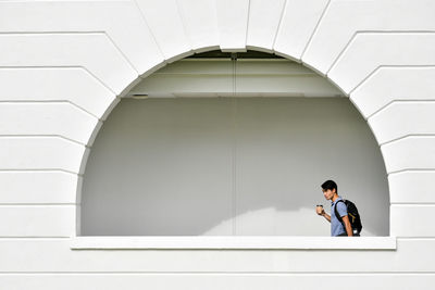 Man looking down while sitting on wall