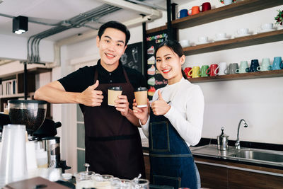 Happy friends standing by people in kitchen