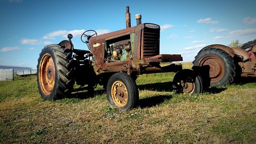 Tractor on field against cloudy sky