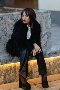 Portrait of young woman standing against wall