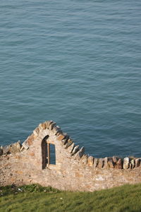 Scenic view of an old stone wall with a small opening overlooking the irish sea in ireland.