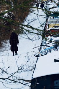 Rear view of woman walking on snow covered tree