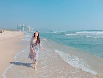 Young woman standing on beach against clear sky