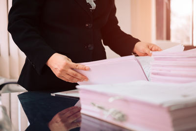 Midsection of woman reading book on table