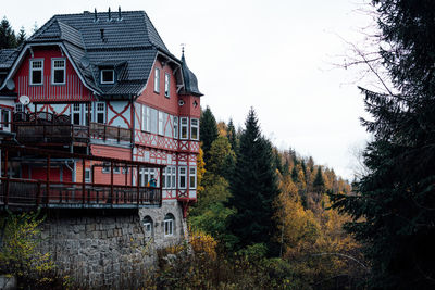 House by trees in forest against sky