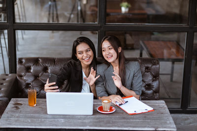 Portrait of smiling young woman using digital tablet in cafe