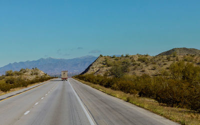 Road by mountains against clear sky