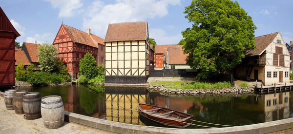 Buildings by river against sky