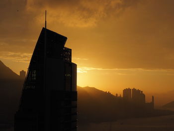 Silhouette of building against cloudy sky at sunset