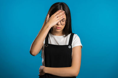 Portrait of beautiful young woman against blue background