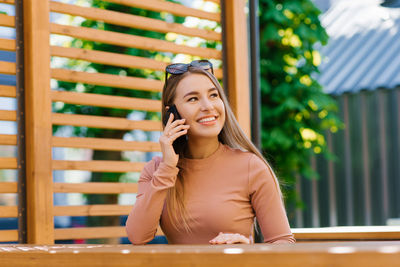 Young charming woman calls on a mobile phone while sitting in a cafe in her free time