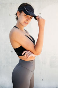 Portrait of young woman standing against wall