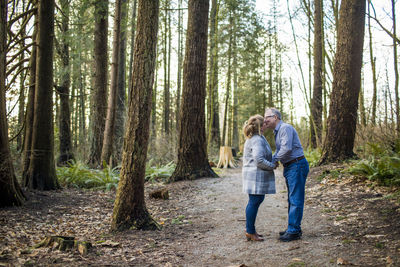 Retired couple kissing in the woods.