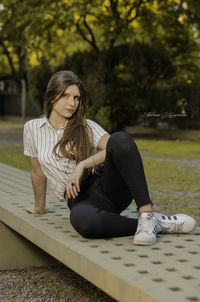 Full length of young woman sitting outdoors