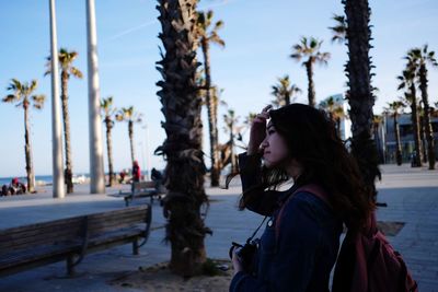 Side view of woman looking away against trees