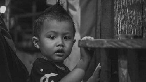 Close-up portrait of cute baby boy by wood