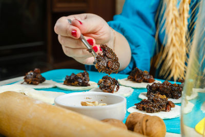 The hands of a jewish woman laying poppy seed filling on the dough for gomentashi cookies