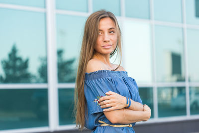 Portrait of a beautiful young woman standing against window