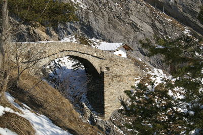 Side view of footbridge against snowed rocks