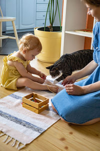 Mother and daughter playing with cat at home