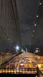 Light trails on bridge in city against sky at night