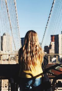 Rear view of woman standing by buildings against sky