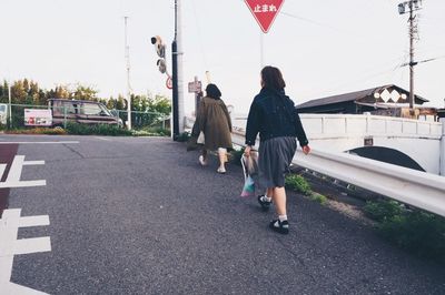 Rear view of woman walking on road against sky