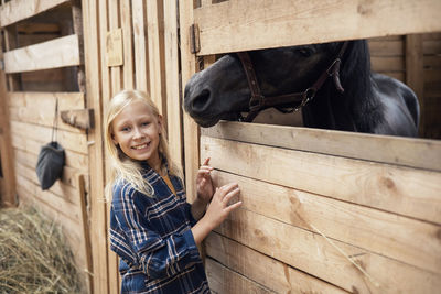 A girl in cowboy-style clothes in the stable