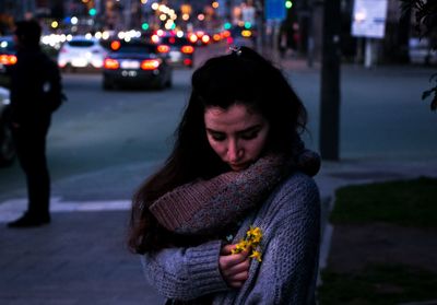 Woman holding flowers in city at night