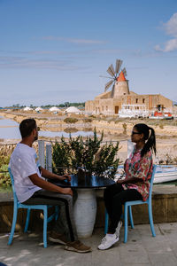 People sitting on chair at table against sky