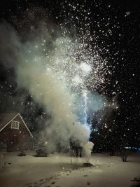 Fireworks explosion with sparks and smoke against sky at night during winter