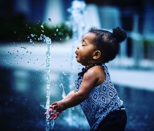 Side view of girl playing with fountain