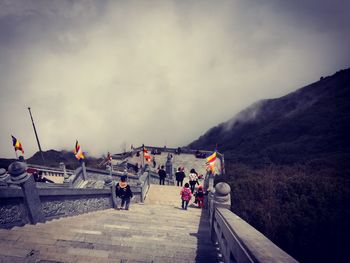 Group of people on road by mountain against sky