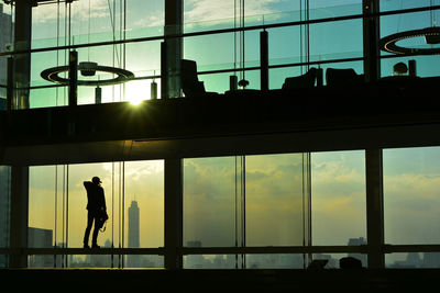 Silhouette man standing in modern building during sunset