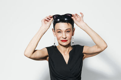 Portrait of young woman with arms crossed against white background