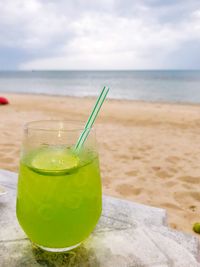 Green drink on table by sea against sky