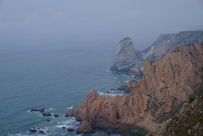 Rock formations by sea against sky