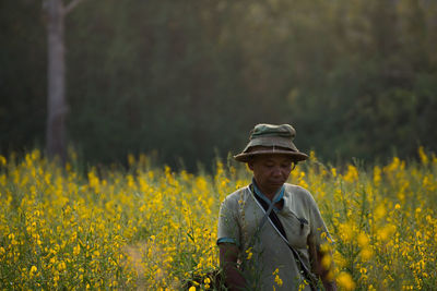 Man looking away while standing amidst plants on field