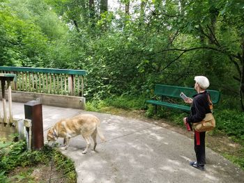 Side view of mid adult man with dog standing on footpath in park